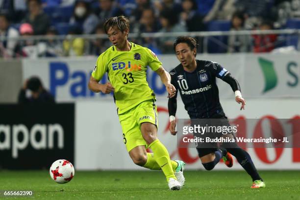 Tsukasa Shiotani of Sanfrecce Hiroshima controls the ball under pressure of Shu Kurata of Gamba Osaka during the J.League J1 match between Gamba...