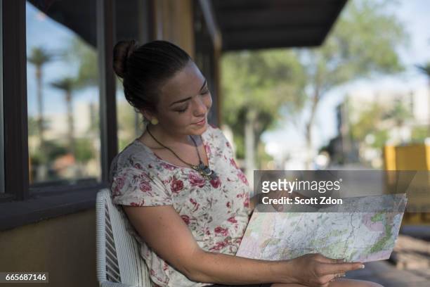 close-up of woman sitting outside cafe looking at map - scott zdon stock-fotos und bilder
