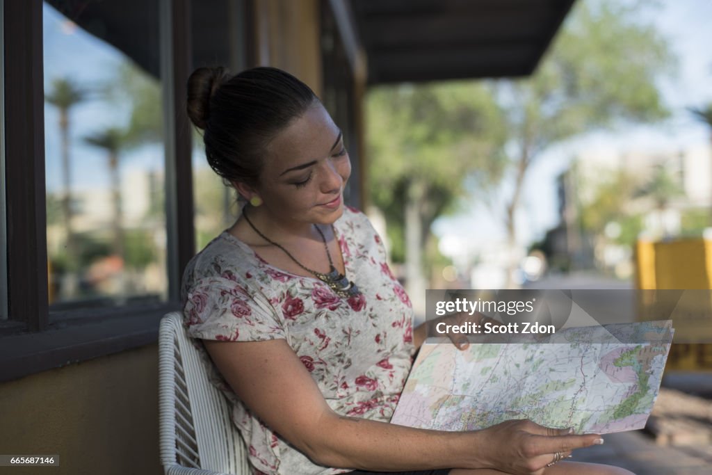 Close-up of woman sitting outside cafe looking at map