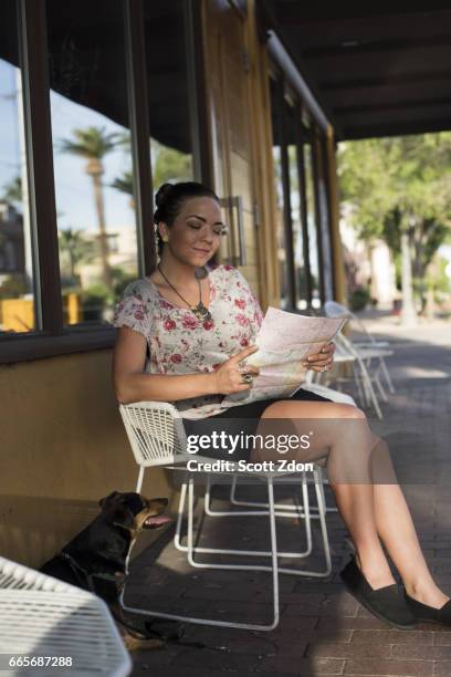 woman sitting outside cafe holding map - scott zdon stock-fotos und bilder