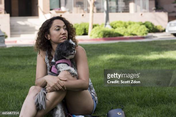 woman sitting in park with dog on her lap - scott zdon fotografías e imágenes de stock