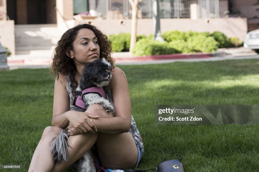 Woman sitting in park with dog on her lap