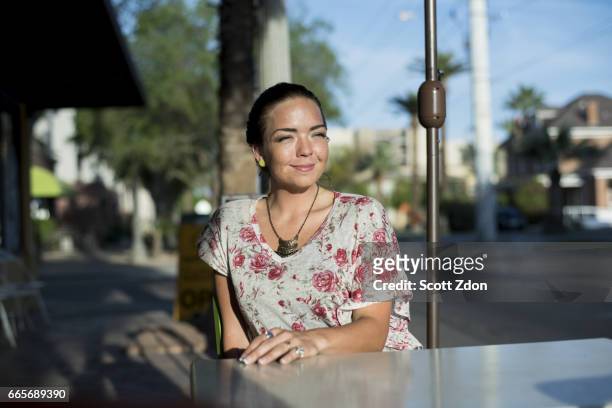 woman sitting outside at neighborhood cafe - scott zdon stock-fotos und bilder