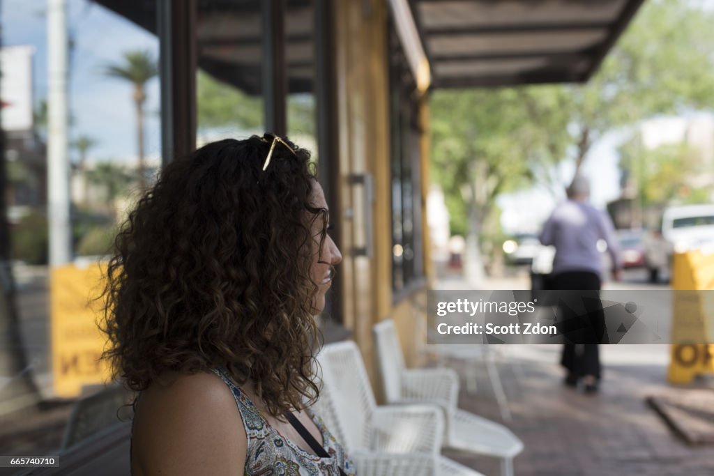 Side view of woman sitting outside neighborhood cafe