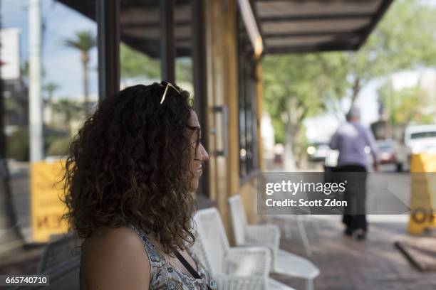 side view of woman sitting outside neighborhood cafe - scott zdon stock pictures, royalty-free photos & images