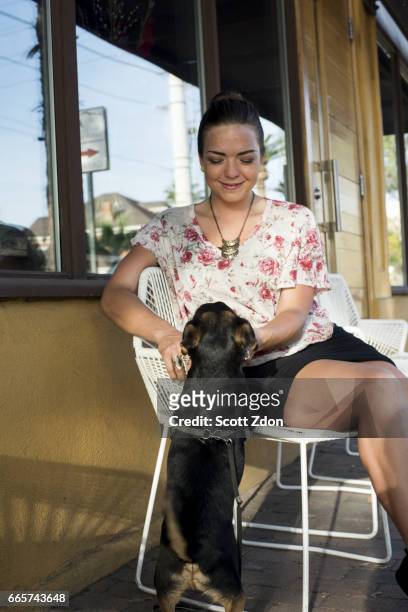 caucasian woman sitting with dog at neighborhood cafe. - scott zdon stock-fotos und bilder