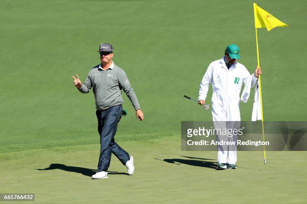 Charley Hoffman of the United States waves on the second green alongside caddie Brett Waldman during the second round of the 2017 Masters Tournament...