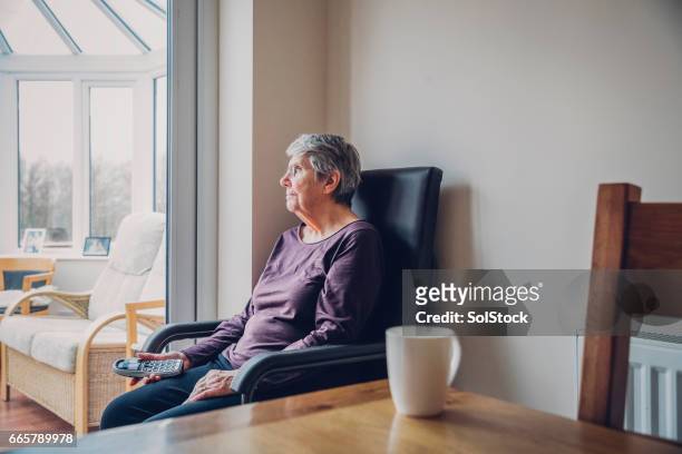 donna anziana seduta da sola - landline phone home foto e immagini stock