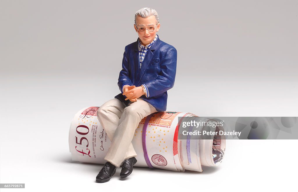 Retired man sitting on roll of UK bank notes