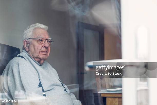 senior man seen through a window - fat man chair stock pictures, royalty-free photos & images