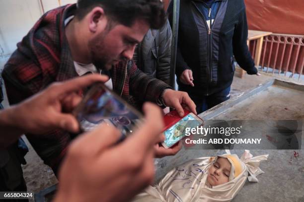 Syrian takes one last picture of his daughter, one-year-old infant Amira, whose body lies in a make-shift morgue, after she died in a reported air...