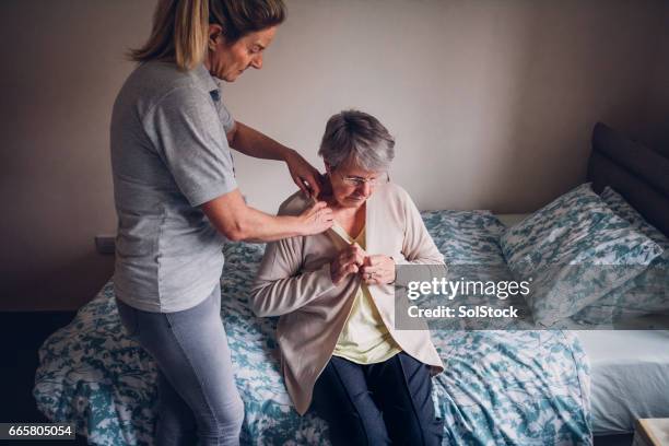 ayuda a domicilio para la mujer mayor en casa - vestirse fotografías e imágenes de stock