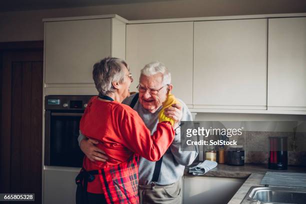 äldre par dans i sin kitcchen - couple laughing hugging bildbanksfoton och bilder