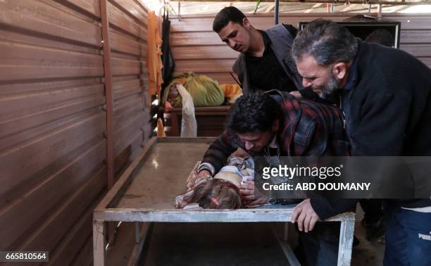 The father of one-year-old infant Amira grieves over her body as others wrap the burial shrowd in a make-shift morgue, after she died in a reported...