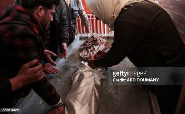Syrian wraps the burial shrowd of one-year-old infant Amira, whose body lies in a make-shift morgue, after she died in a reported air strike on the...