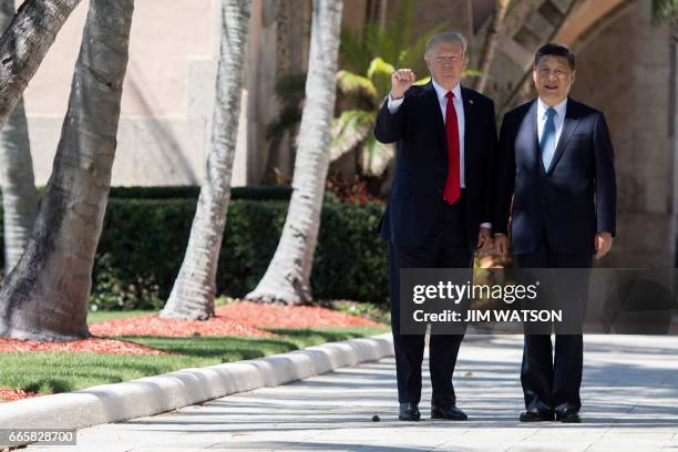 President Donald Trump pumps his fist as he and Chinese President Xi Jinping walk together at the Mar-a-Lago estate in West Palm Beach, Florida,...