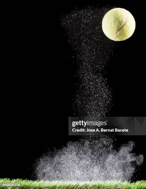 ball of tennis striking and  bouncing on a surface of powder on a black background - césped stock-fotos und bilder