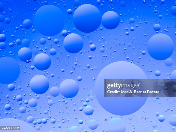 full frame of the textures formed by the bubbles and drops of oil in the shape of circle floating on a blue colors background - contaminación photos et images de collection