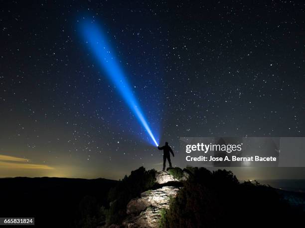 silhouette of a man doing signs with a lantern on the horizon in the night - silueta stockfoto's en -beelden