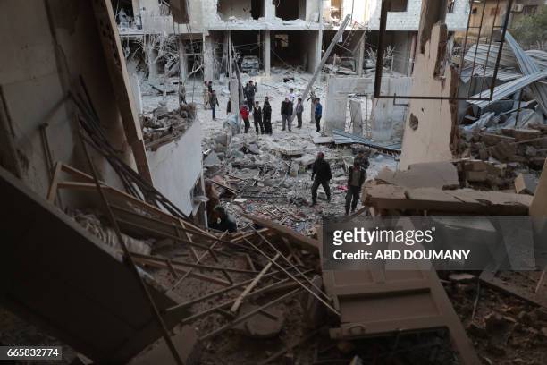 Syrians look a the damage following a reported air strike by government forces in the rebel-held town of Douma, on the eastern outskirts of Damascus,...