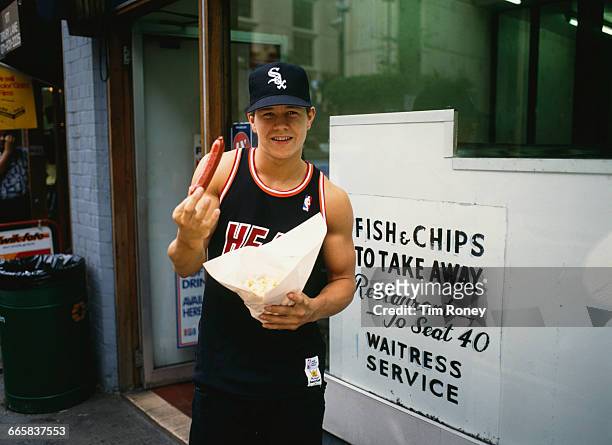 Marky Mark, singer and rapper of the Funky Bunch, posing with a sausage outside a fish and chip shop in London, circa 1991.