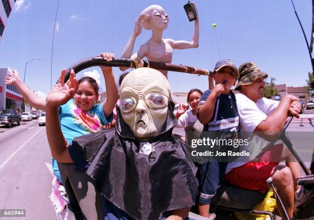 Groups dressed as aliens ride through downtown Roswell, New Mexico July 1, 2000 as they participate in the annual UFO Encounter, which runs through...