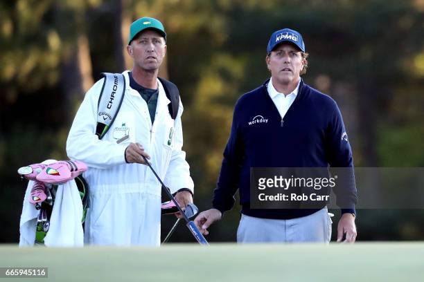 Phil Mickelson of the United States and caddie Jim Mackay watch a chip shot on the 18th hole during the second round of the 2017 Masters Tournament...