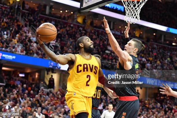Kyrie Irving of the Cleveland Cavaliers passes around Ryan Kelly of the Atlanta Hawks during the first half at Quicken Loans Arena on April 7, 2017...