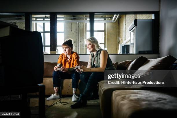 female colleagues playing old video game in office - video game stock-fotos und bilder