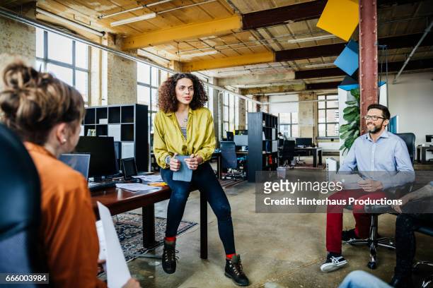 casual businesswoman leading an informal team meeting - startup photos et images de collection