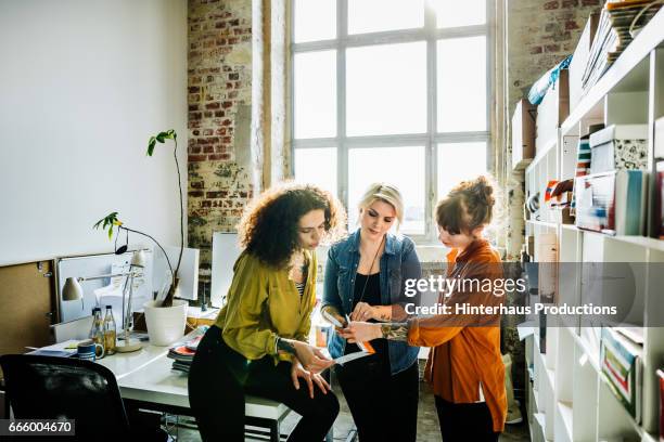 businesswomen having an informal meeting in a large office space - camisa cor de laranja - fotografias e filmes do acervo