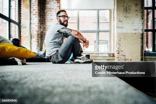 casual business person sitting in office loft - loft office bildbanksfoton och bilder