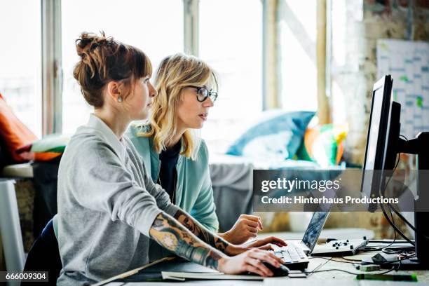 two businesswomen working on a computer - millennials working ストックフォトと画像
