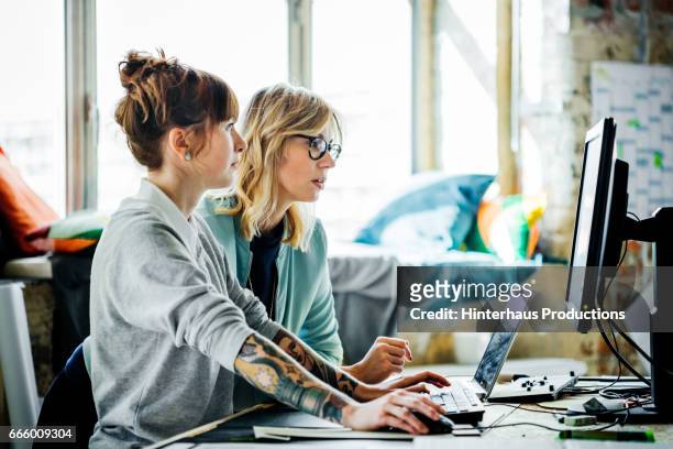 two businesswomen working on a computer - women working stockfoto's en -beelden