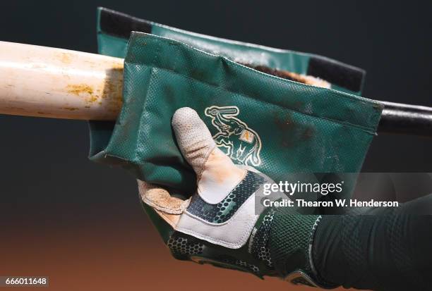 Yonder Alonso of the Oakland Athletics puts pinetar on his bat in the on-deck circle against the Los Angeles Angels of Anaheim in the bottom of the...