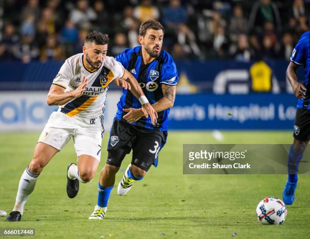 Romain Alessandrini of Los Angeles Galaxy charges as Hernan Bernardello of Montreal Impact defends during Los Angeles Galaxy's MLS match against...