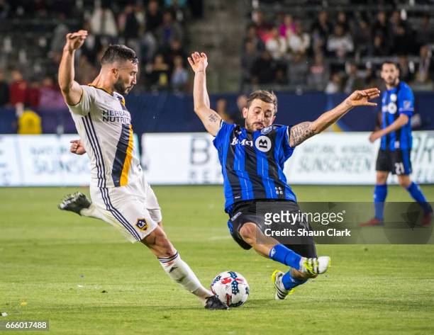 Romain Alessandrini of Los Angeles Galaxy takes a shot as Hernan Bernardello of Montreal Impact defends during Los Angeles Galaxy's MLS match against...