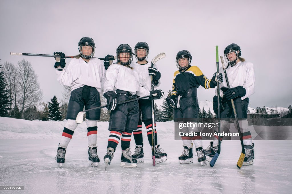 Teenage girl ice hockey players standing on outdoor rink in winter