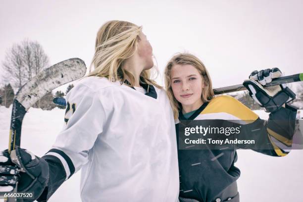 two teenage girl ice hockey players standing on rink outdoors in winter - girls ice hockey stock pictures, royalty-free photos & images