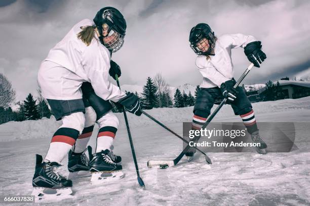 teenage girl ice hockey players clashing on outdoor rink in winter - hockey helmet stock pictures, royalty-free photos & images