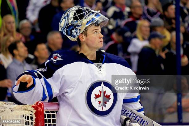 Eric Comrie of the Winnipeg Jets watches a replay after letting in a goal while making his NHL debut during the game against the Columbus Blue...