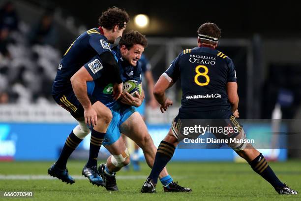 Matt Moulds of the Blues tries to break the tackle of Marty Banks and Luke Whitelock of the Highlanders during the round seven Super Rugby match...