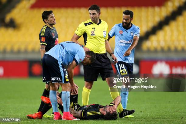 Vince Lia of the Phoenix and Alex Brosque of Sydney FC talk to referee Shaun Evans while Tom Doyle of the Phoenix recovers from a tackle during the...