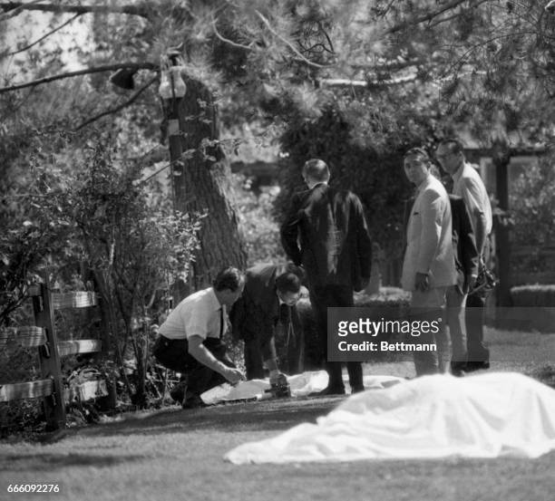 County coroner's office take notes and look at the bodies found on the lawn of the Sharon Tate-Roman Polanski home. Five people were discovered...