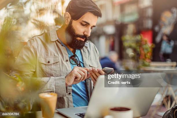 portrait of young man with long beard working at cafe - middle east cool stock pictures, royalty-free photos & images