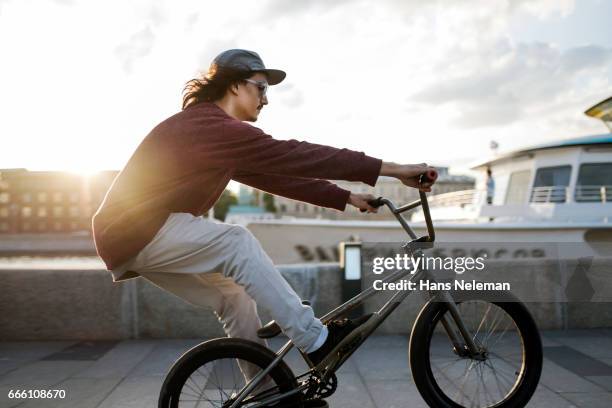 bmx rider performing bicycle stunt - bicycle stunt stock pictures, royalty-free photos & images