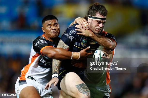 Ethan Lowe of the Cowboys is tackled by the Tigers defence during the round six NRL match between the North Queensland Cowboys and the Wests Tigers...