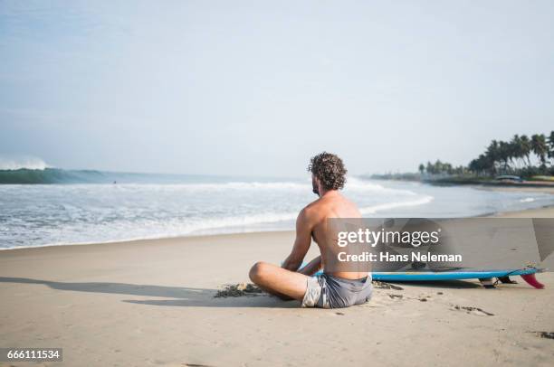 male surfer stretching on the beach - kerala surf stockfoto's en -beelden