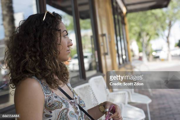 close-up of woman sitting outside neighborhood cafe - scott zdon stock-fotos und bilder