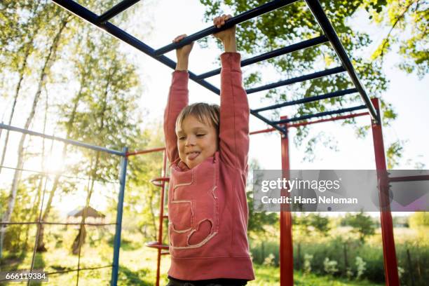 boy playing on monkey bars at playground - boy on monkey bars stock pictures, royalty-free photos & images